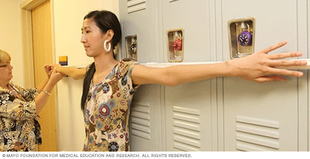 Young woman having the length of her arm span measured