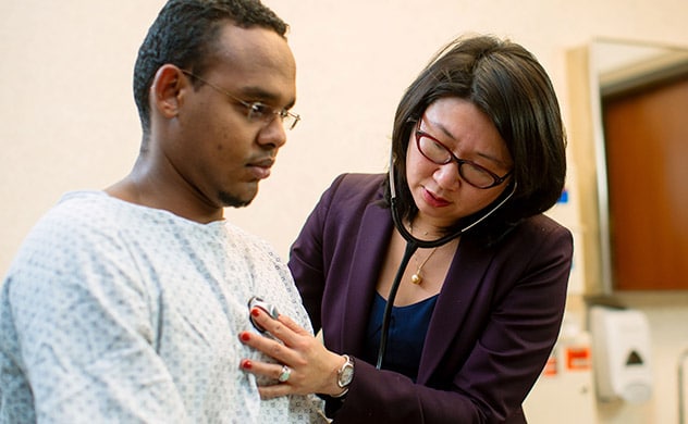 A doctor holds a stethoscope to a patient's chest.