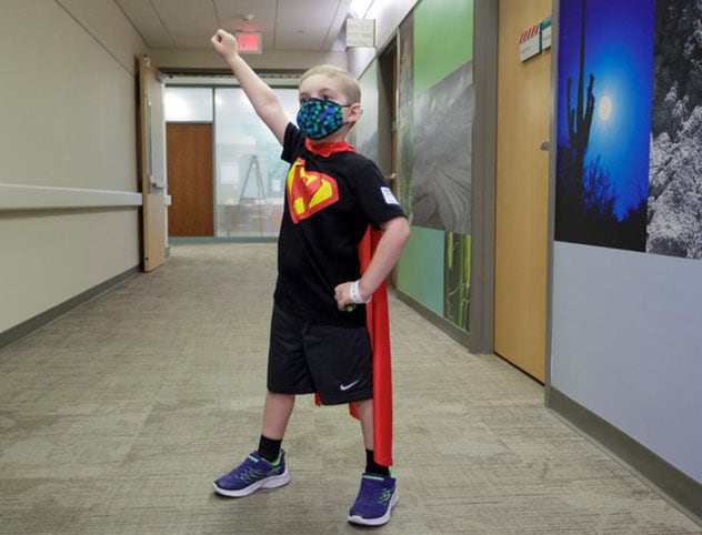 一个穿着超人斗篷的孩子摆出英雄的姿势。